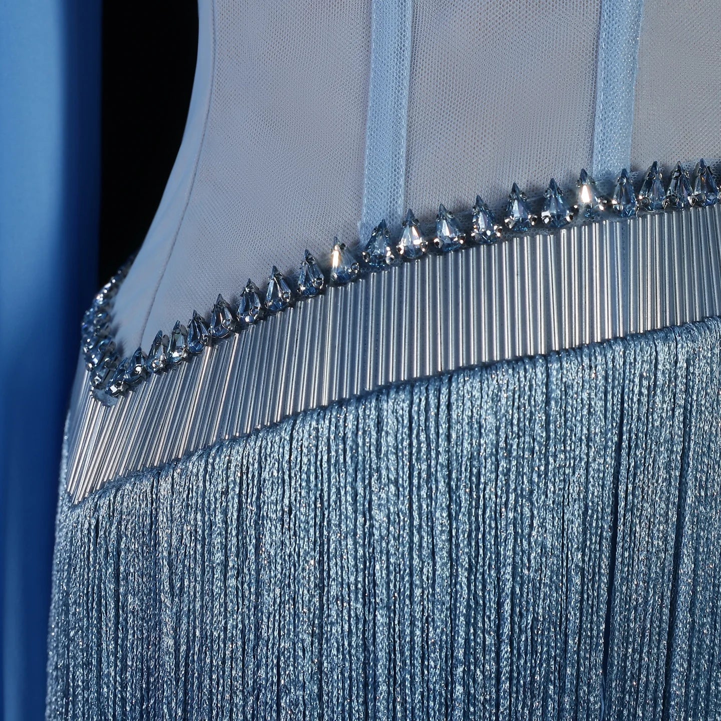 Close-up of a luxury fashion blue evening gown with crystal embellishments on a dark background