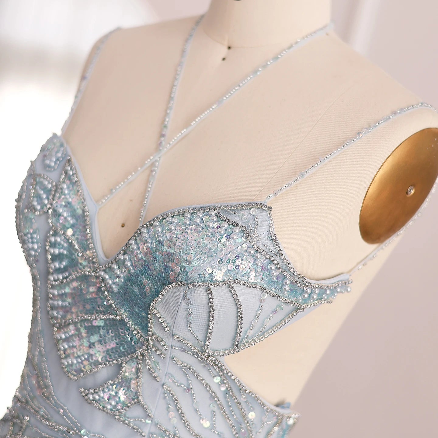 Close-up of a sparkling blue evening gown on a mannequin with a white background
