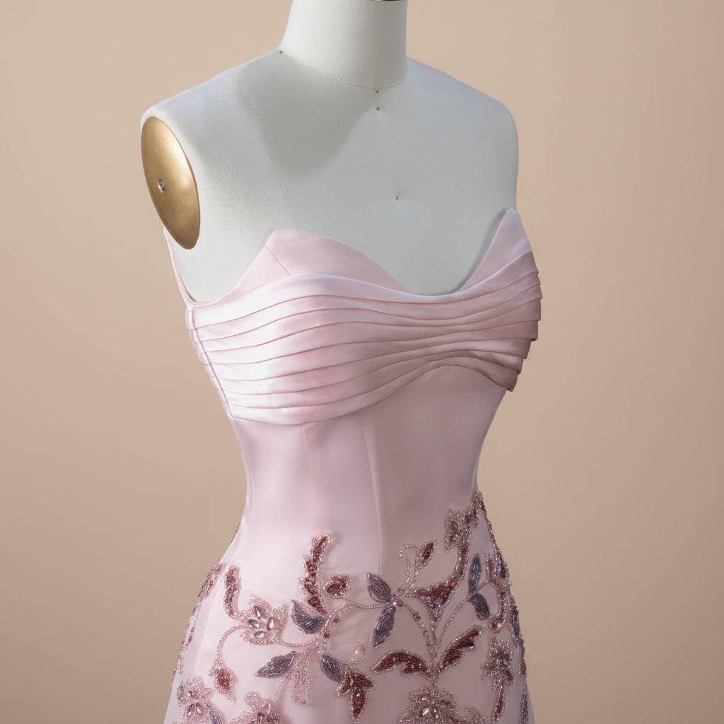 Elegant Pink strapless evening gown with floral crystal embellishments on a mannequin against a beige background