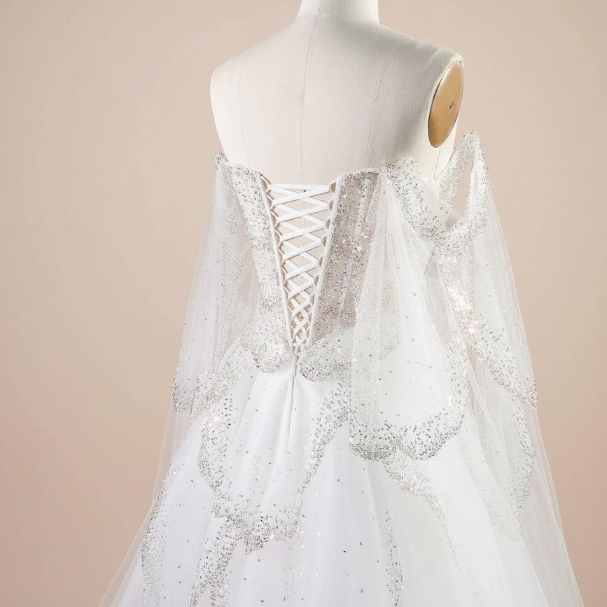 Couture fashion White wedding dress with corset lace up back and silver shiny embellishments on a mannequin against a light background