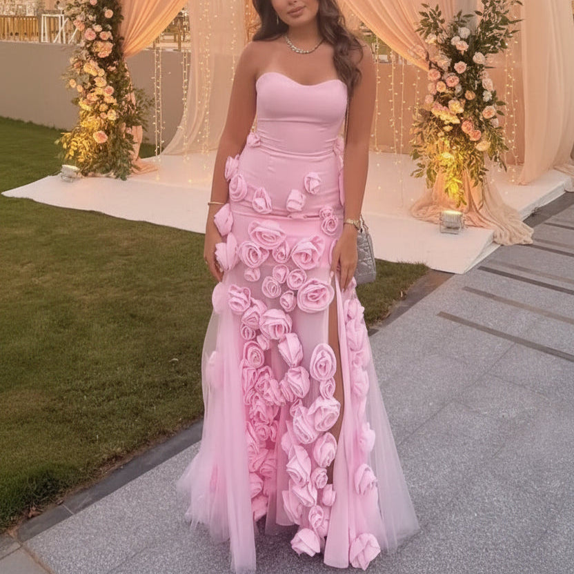 Woman in a stunning pink luxury floral dress standing in front of a decorated outdoor setting with flowers and lights.
