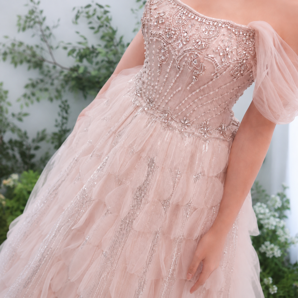 Close-up of a beautiful blush pink beaded evening ballgown with a blurred natural background