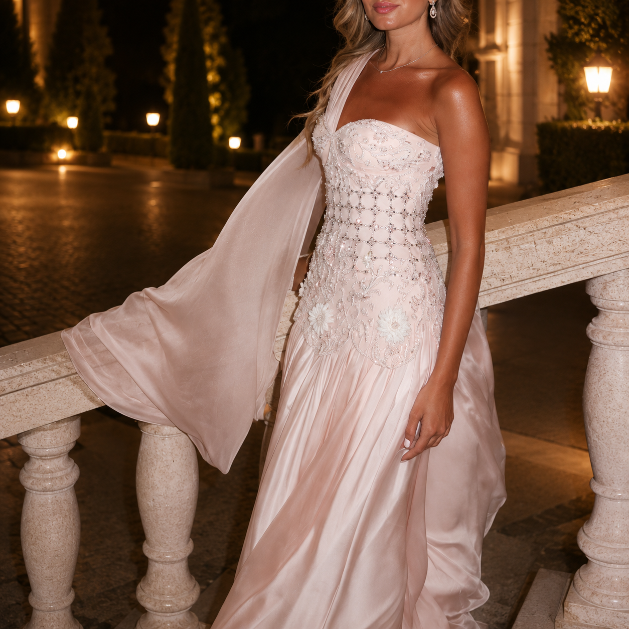 Woman in a elegant couture inspired wedding dress standing on a stone railing at night.