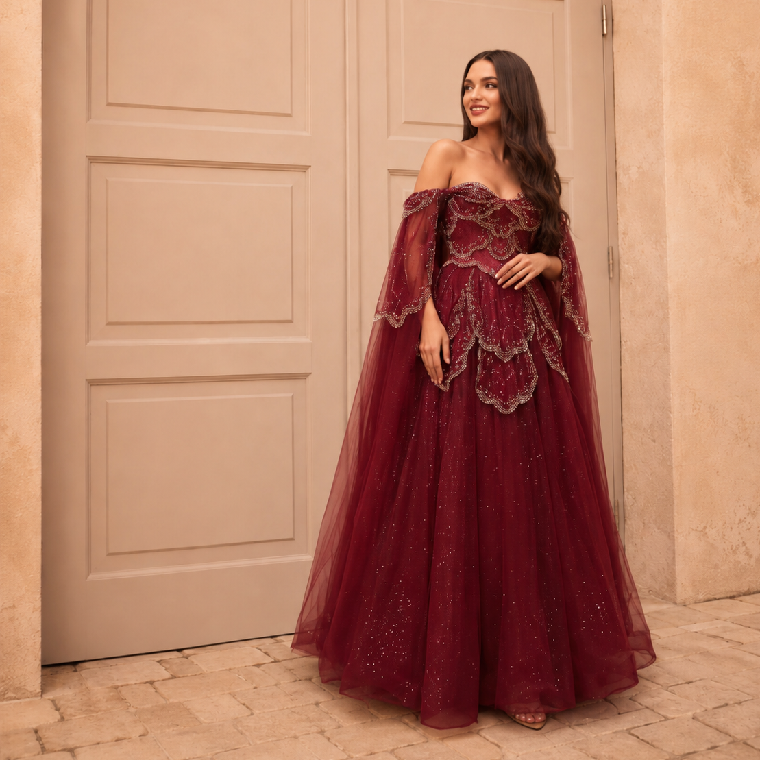 Woman in a stunning luxury fashion burgundy red ballgown with sparkling embellishments standing in front of a decorative door.