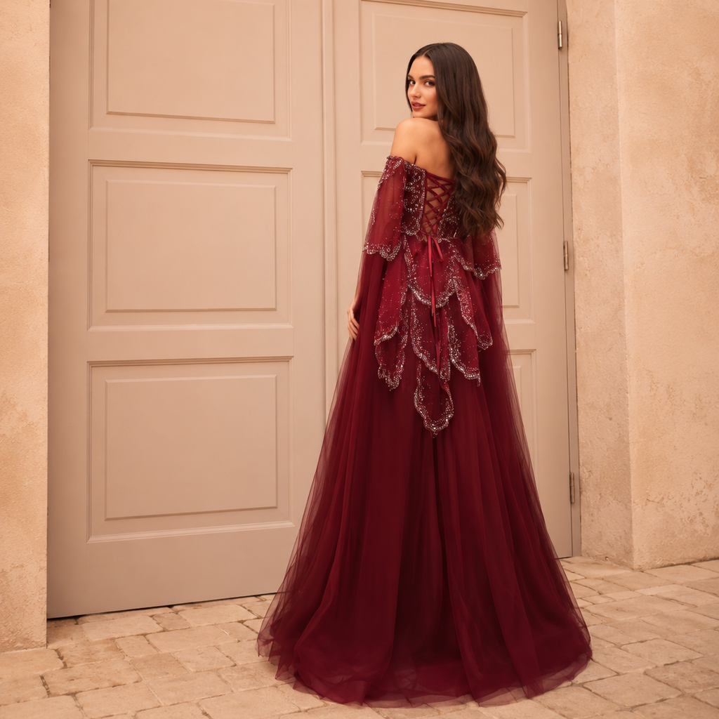 Gorgeous woman in an elegant princess style red burgundy ballgown standing in front of ornate doors.