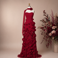 Luxury long red detailed floral prom gown on a mannequin with a beige background and floral arrangement.
